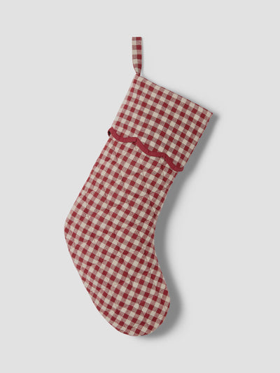 A red and cream gingham Christmas stocking with a red scalloped trim and a matching hanging loop, shown against a light gray background.