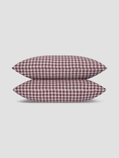 Two pillows stacked vertically, featuring a classic red and white gingham checkered pattern, set against a solid light gray background.