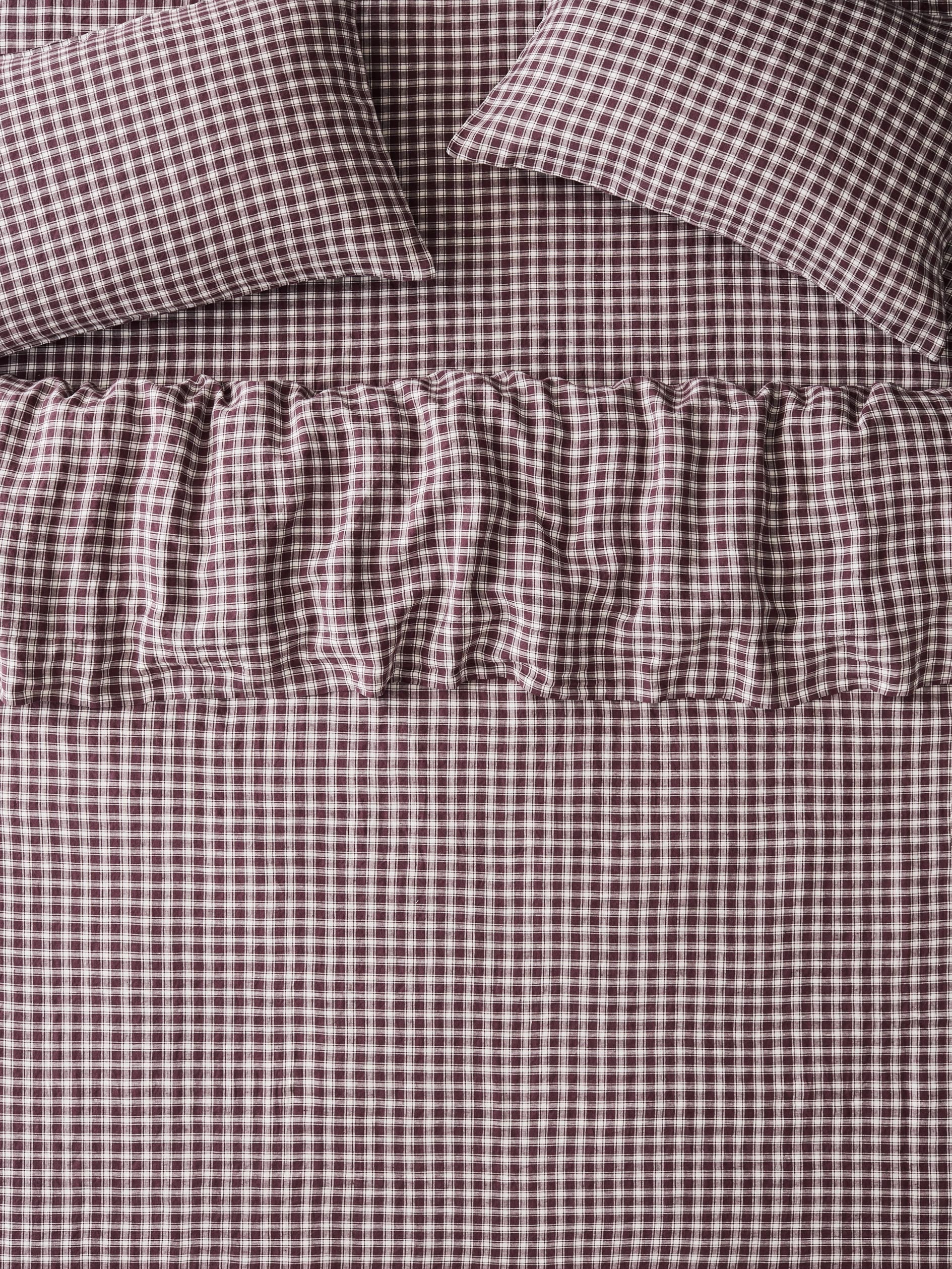 Brown and white gingham check bedding set including a sheet, pillowcases, and a ruffled bed skirt.