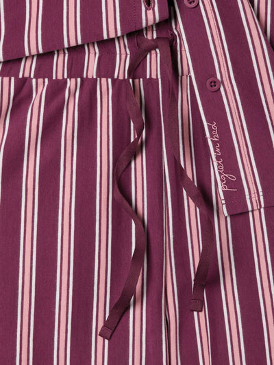 Close up of drawstring pajama trousers with pink and rhubarb red vertical stripes.