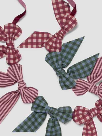 Six fabric bows in various patterns (checkered and striped) in shades of burgundy, green, and blue, arranged on a light gray background.