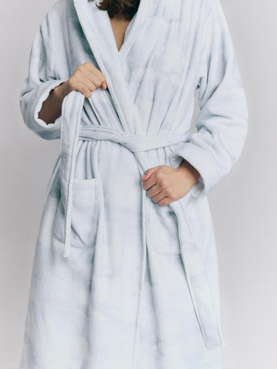 Person wearing a light blue robe against a plain background
