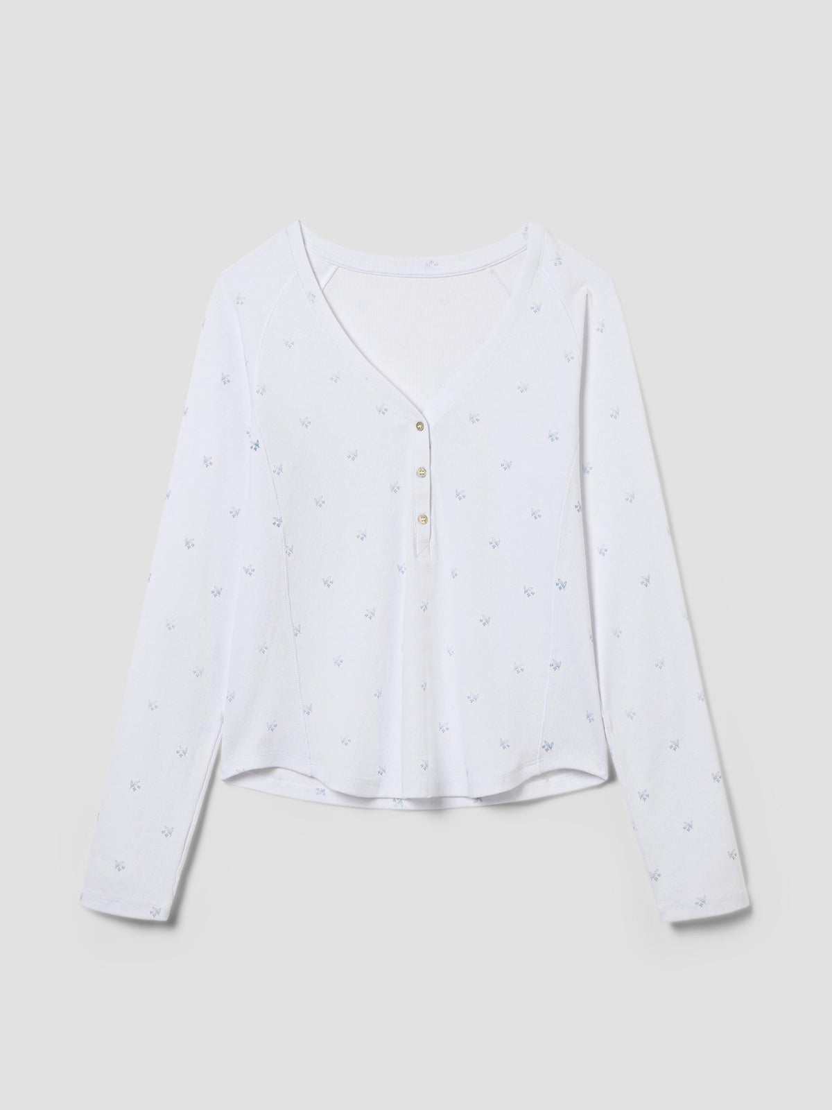 A white long-sleeve henley top with a subtle all-over small heart pattern and a buttoned V-neck front, displayed on a neutral light gray background.