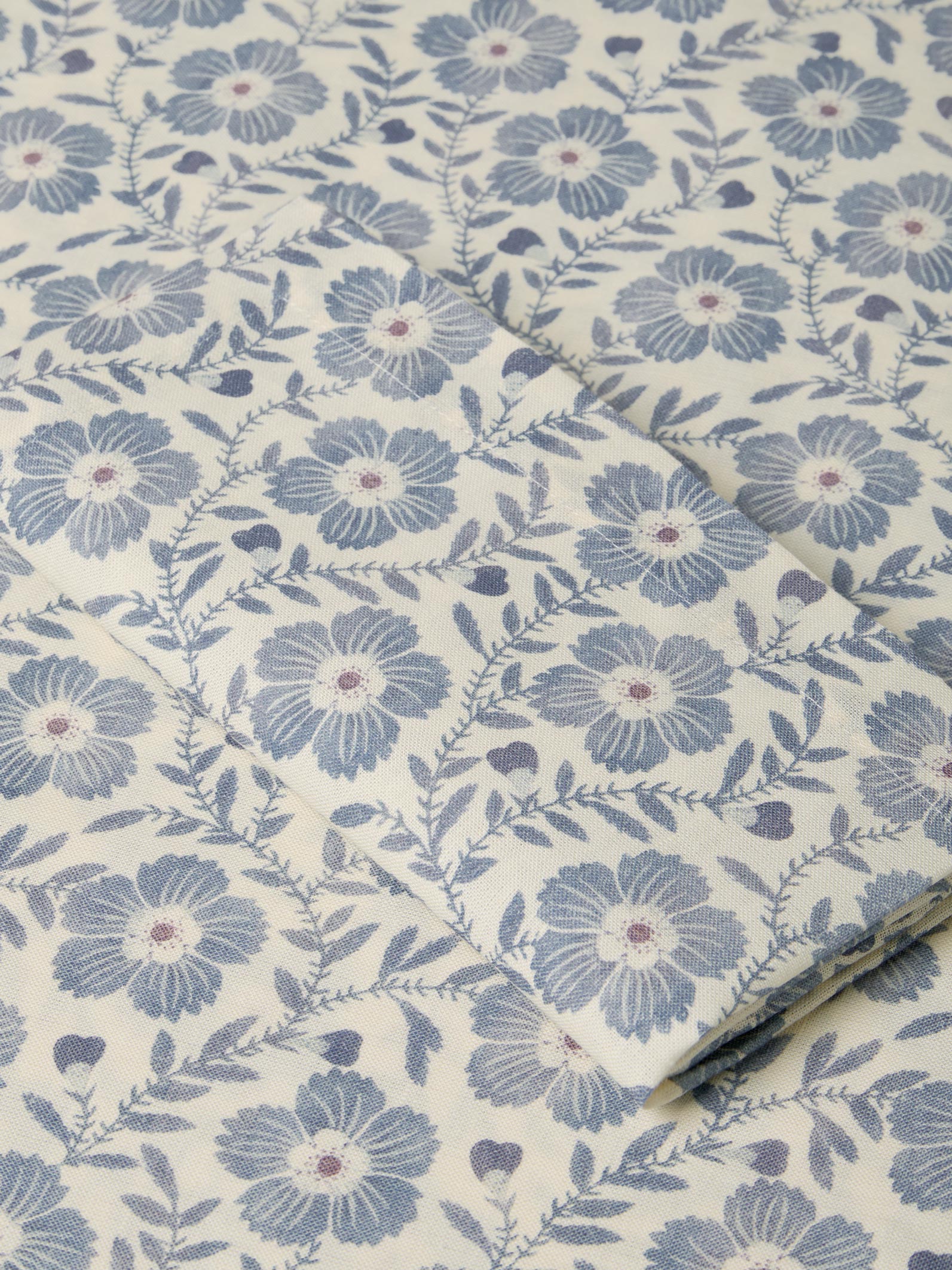 Roll of fabric with blue floral pattern on a beige background