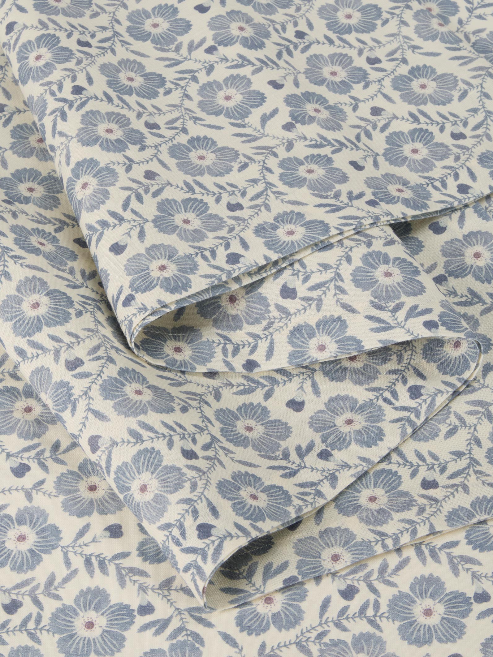 Roll of fabric with a blue floral pattern on a beige background