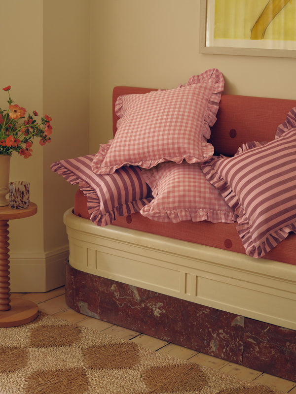 Pink gingham cushions next to striped cushions on a couch