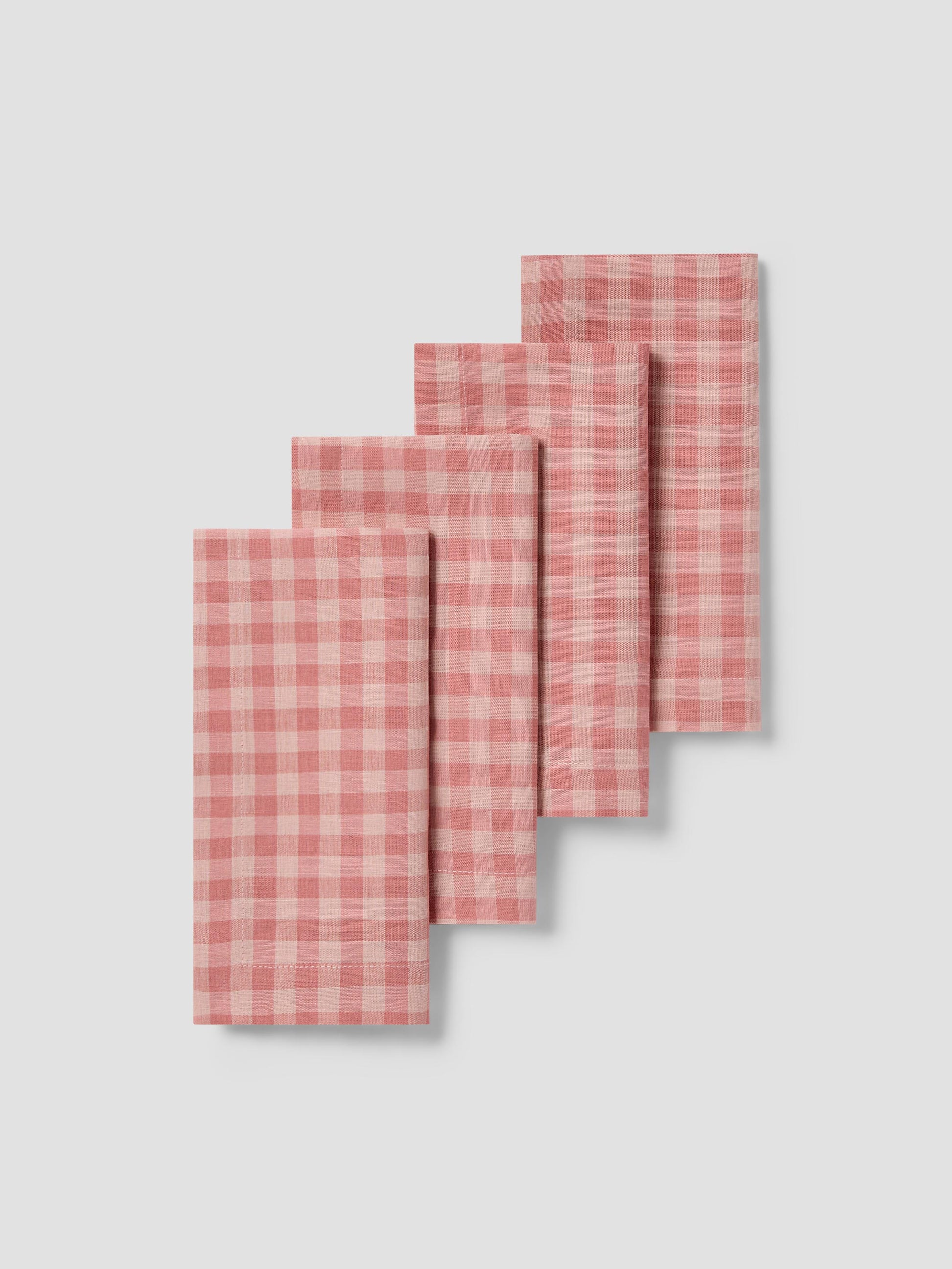 Set of four pink checkered napkins on a light gray background
