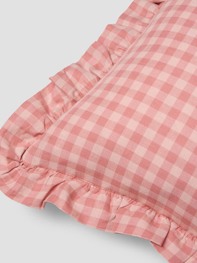 Close up of pink gingham cushion with frill edge on a grey background