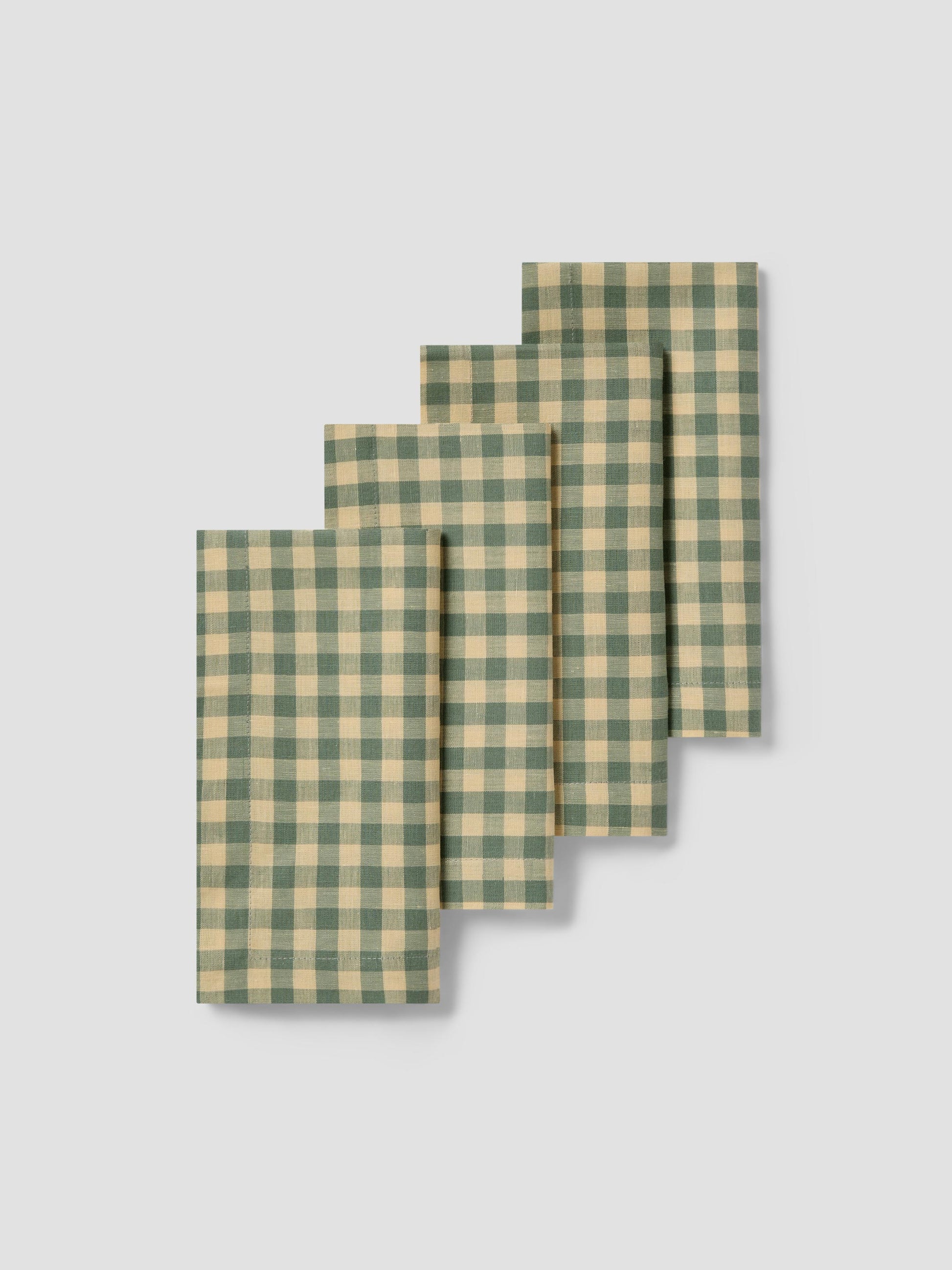 Set of four green and yellow checkered napkins on a light gray background