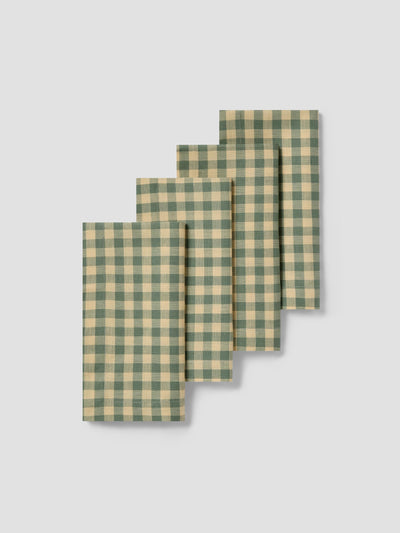 Set of four green and yellow checkered napkins on a light gray background