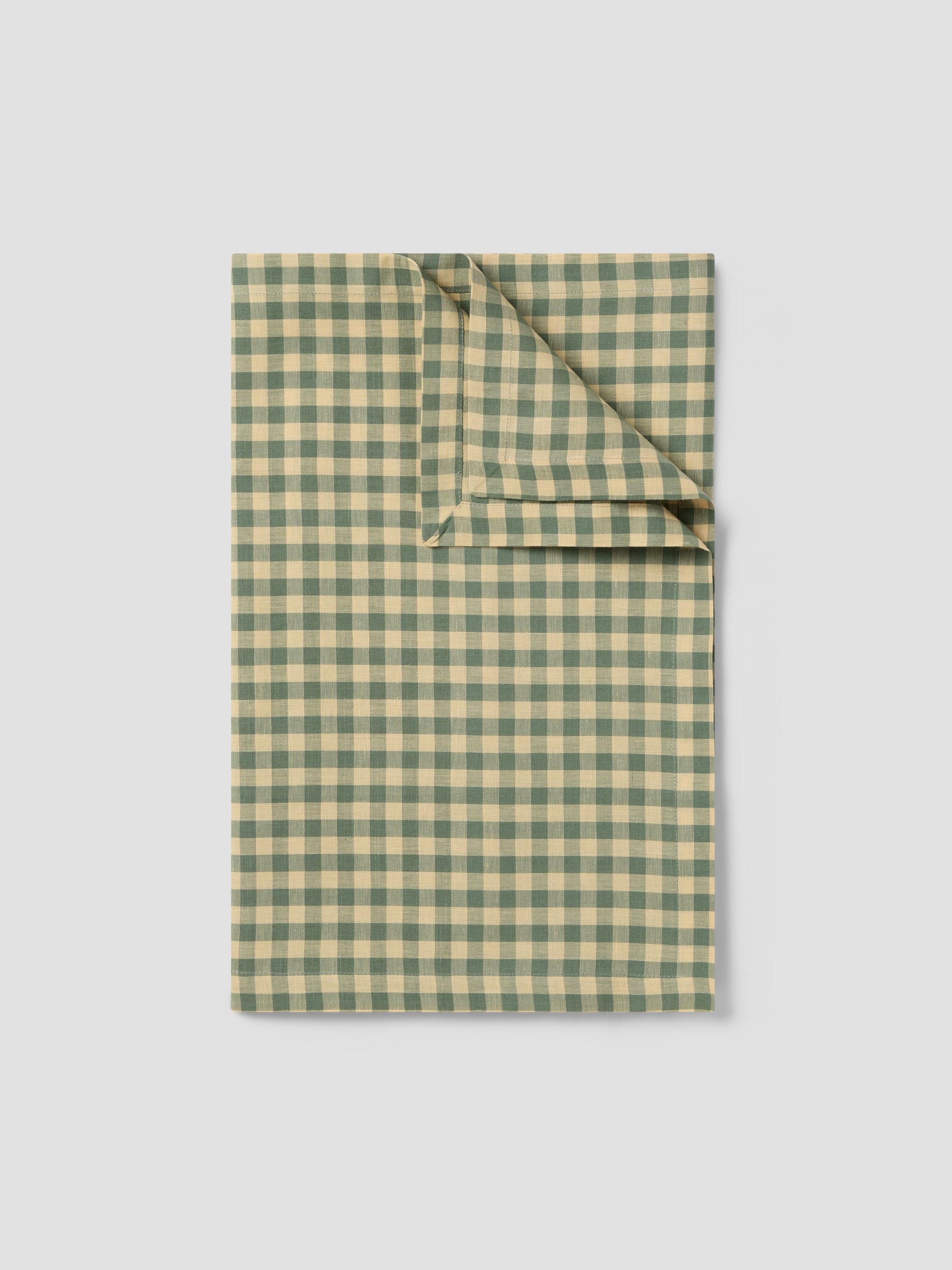 Folded green and beige checkered fabric on a light gray background