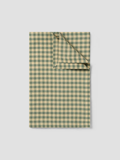 Folded green and beige checkered fabric on a light gray background