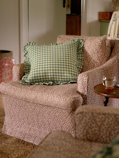 Patterned armchair with a green checkered pillow in a room setting.