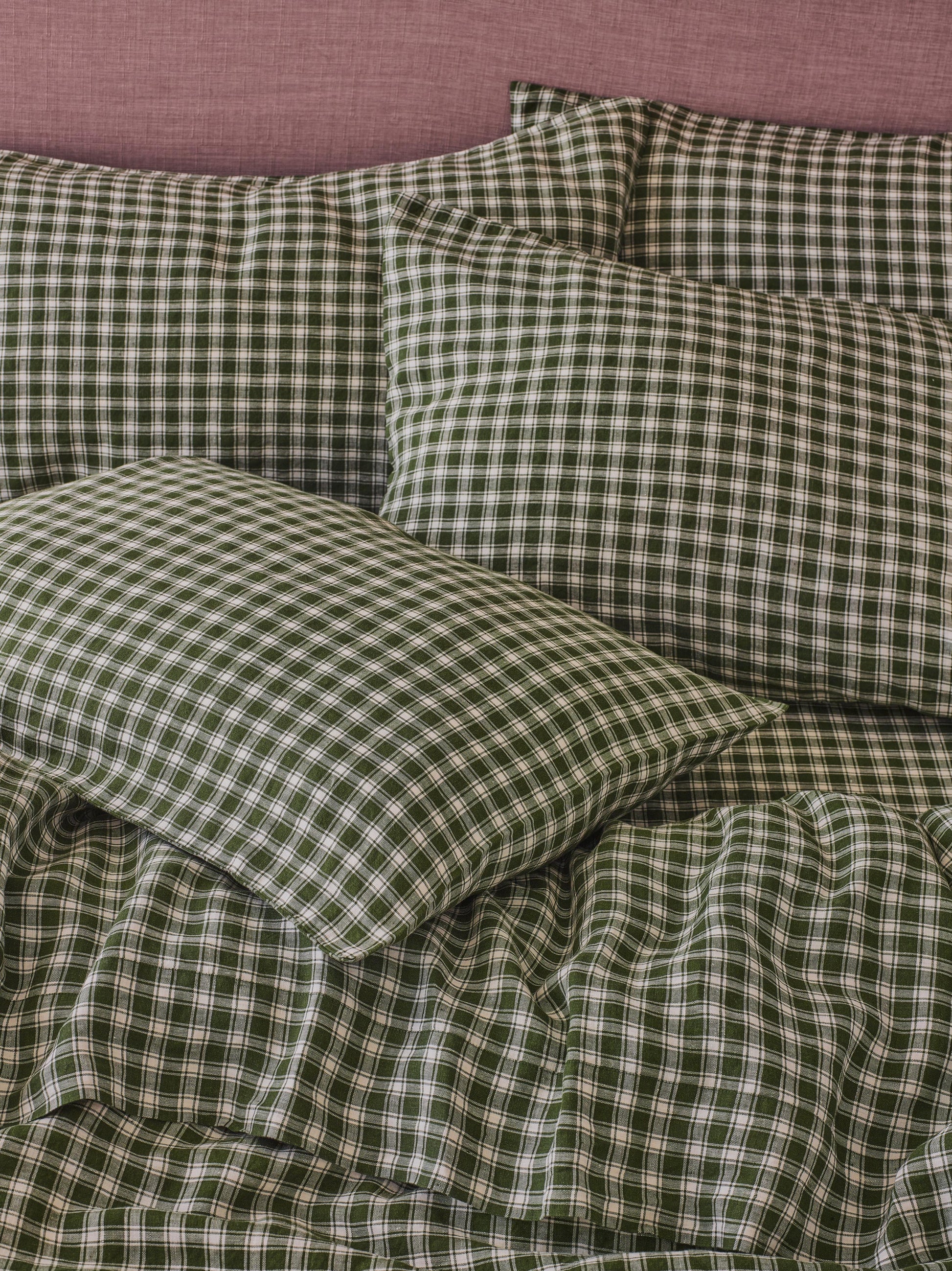 Green and white gingham check bedding set including a duvet cover and matching pillowcases, styled on a bed against a dusty pink headboard.