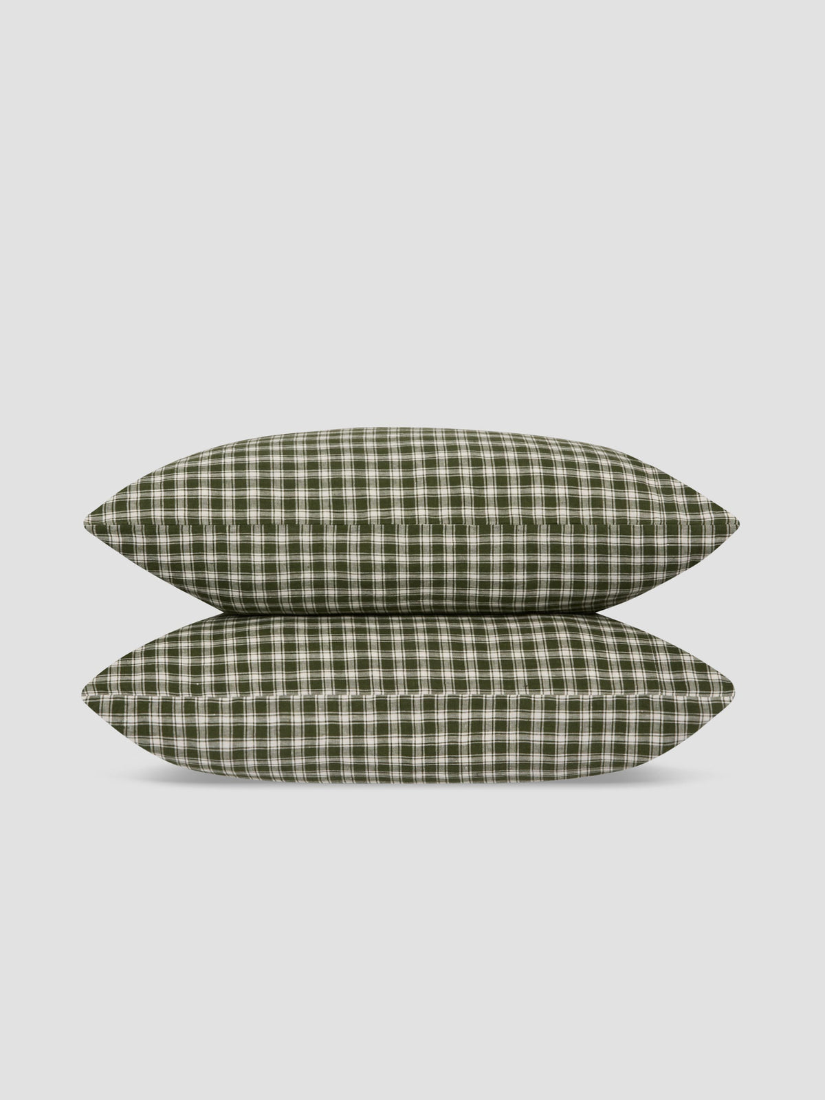Two pillows stacked on top of each other, featuring an olive green and white gingham plaid pattern, set against a solid light gray background.