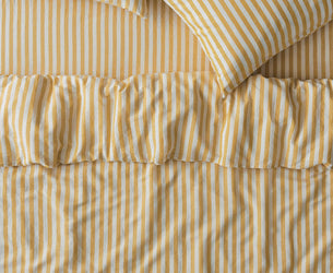 Yellow and white striped bedding set including a duvet cover with a ruffled hem and two matching pillowcases.