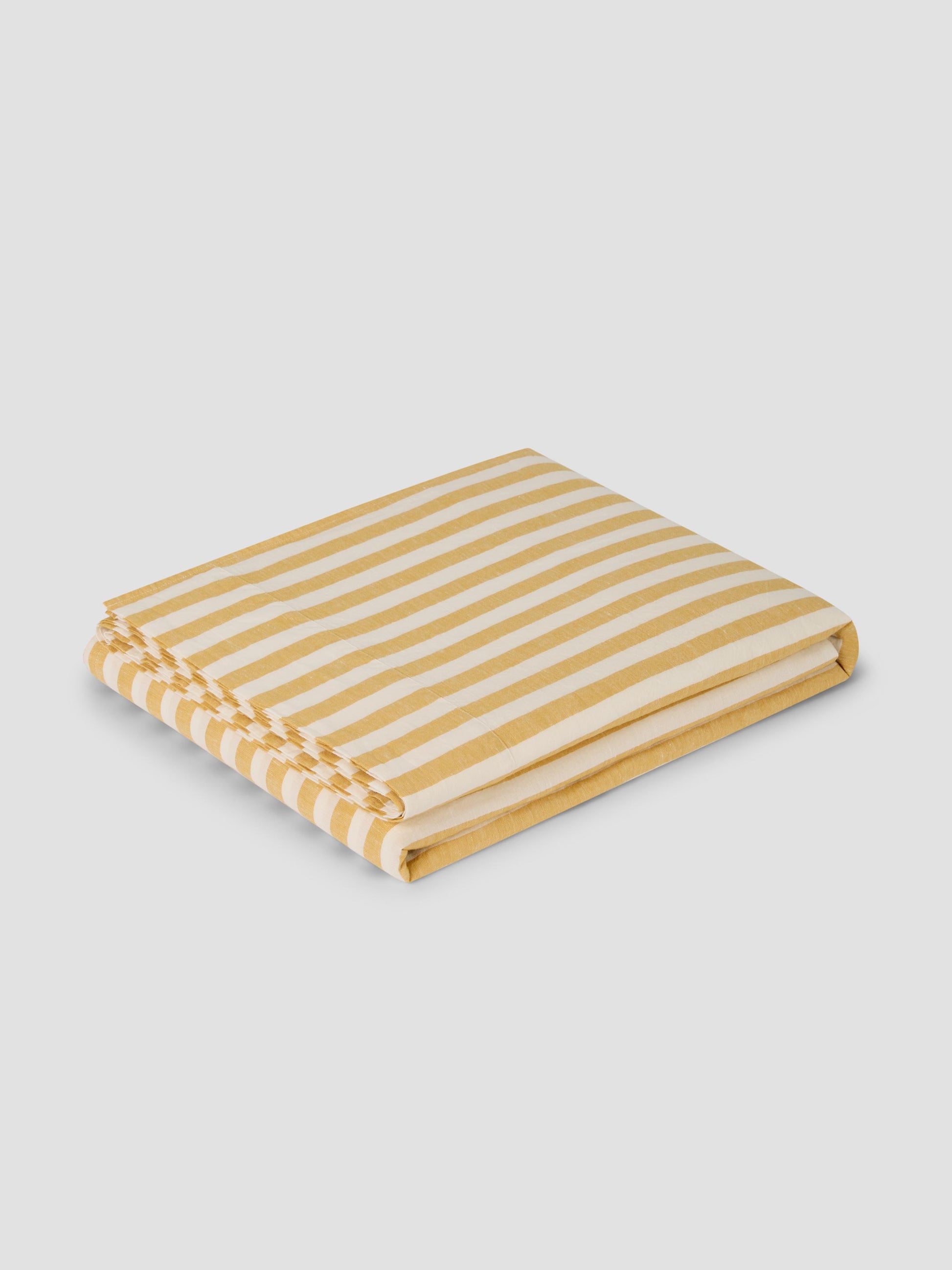 Yellow and Cream flat sheet folded up on a grey background.