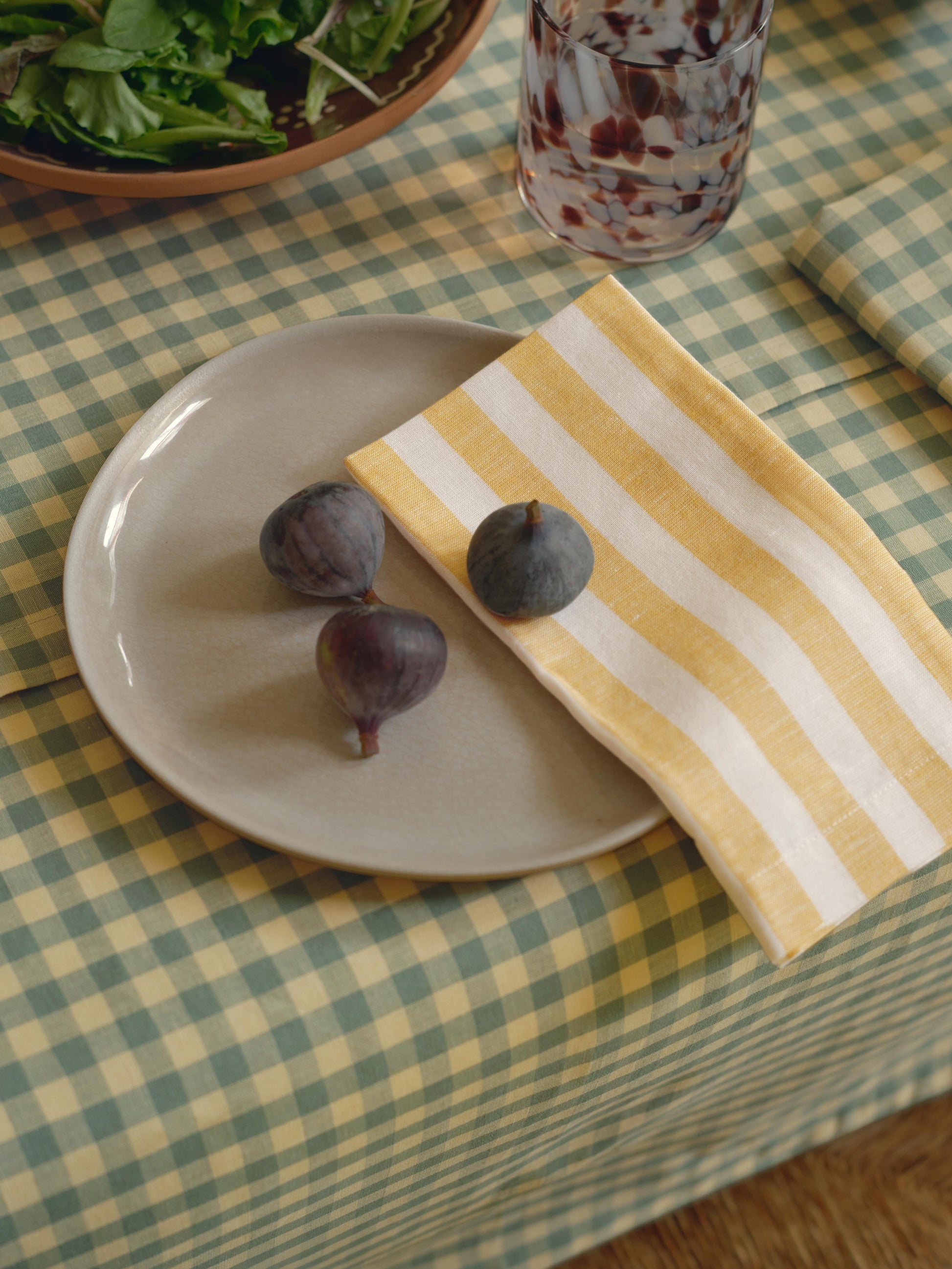 Plate with figs on a checkered tablecloth with a yellow striped napkin.