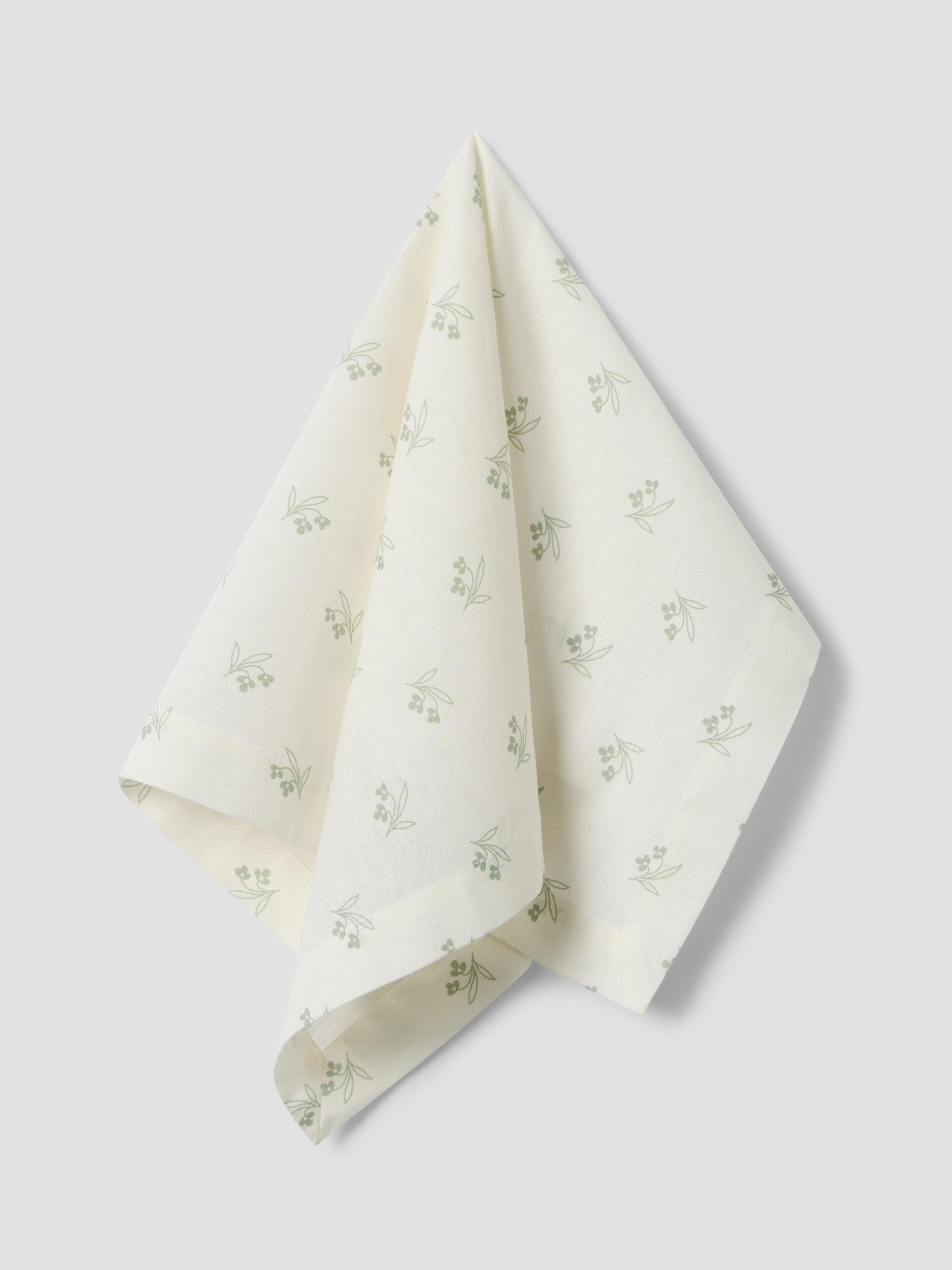 White fabric with green floral pattern on a light gray background