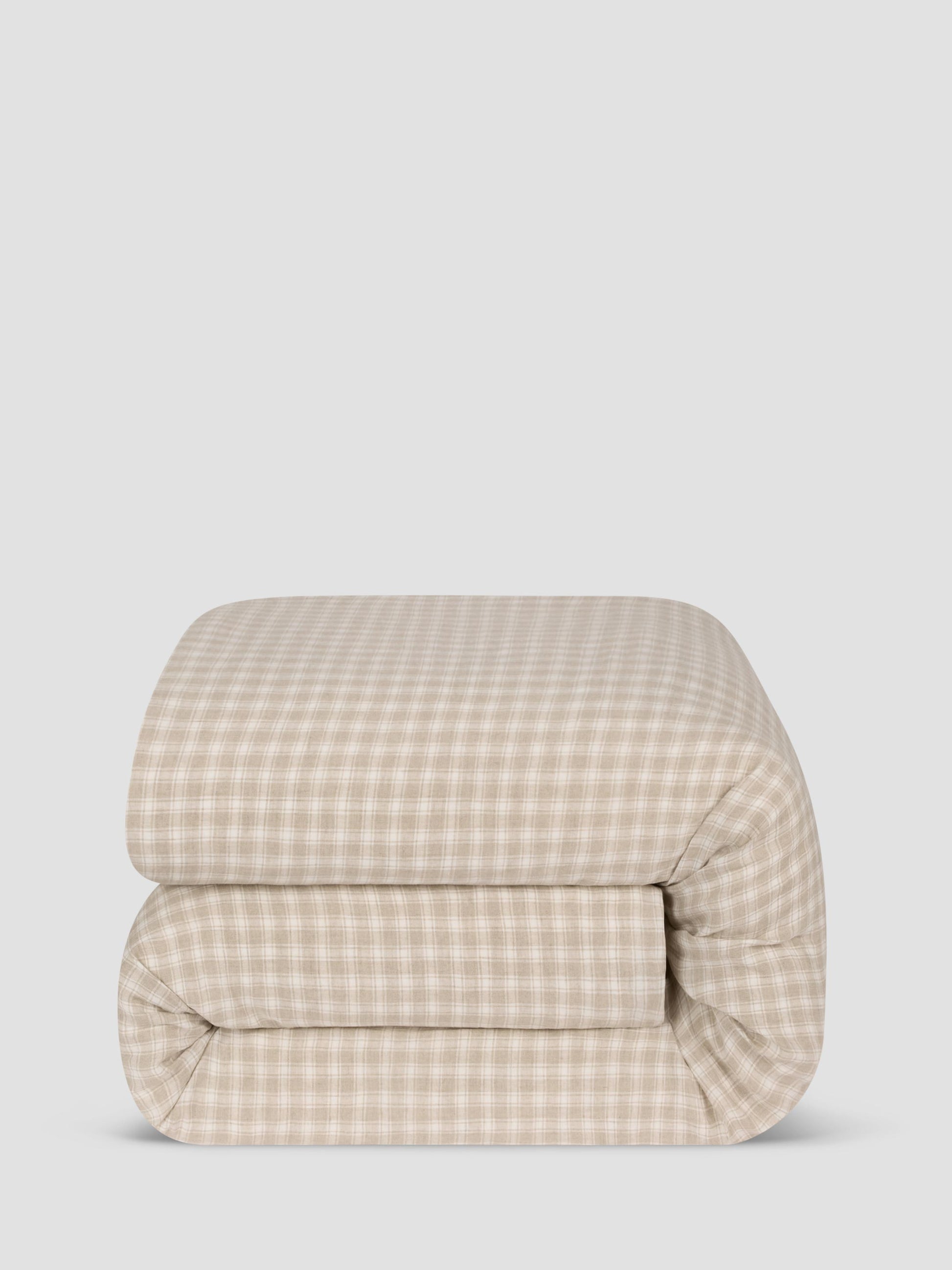 A folded comforter, featuring a beige and white gingham check pattern, set against a solid light gray background.