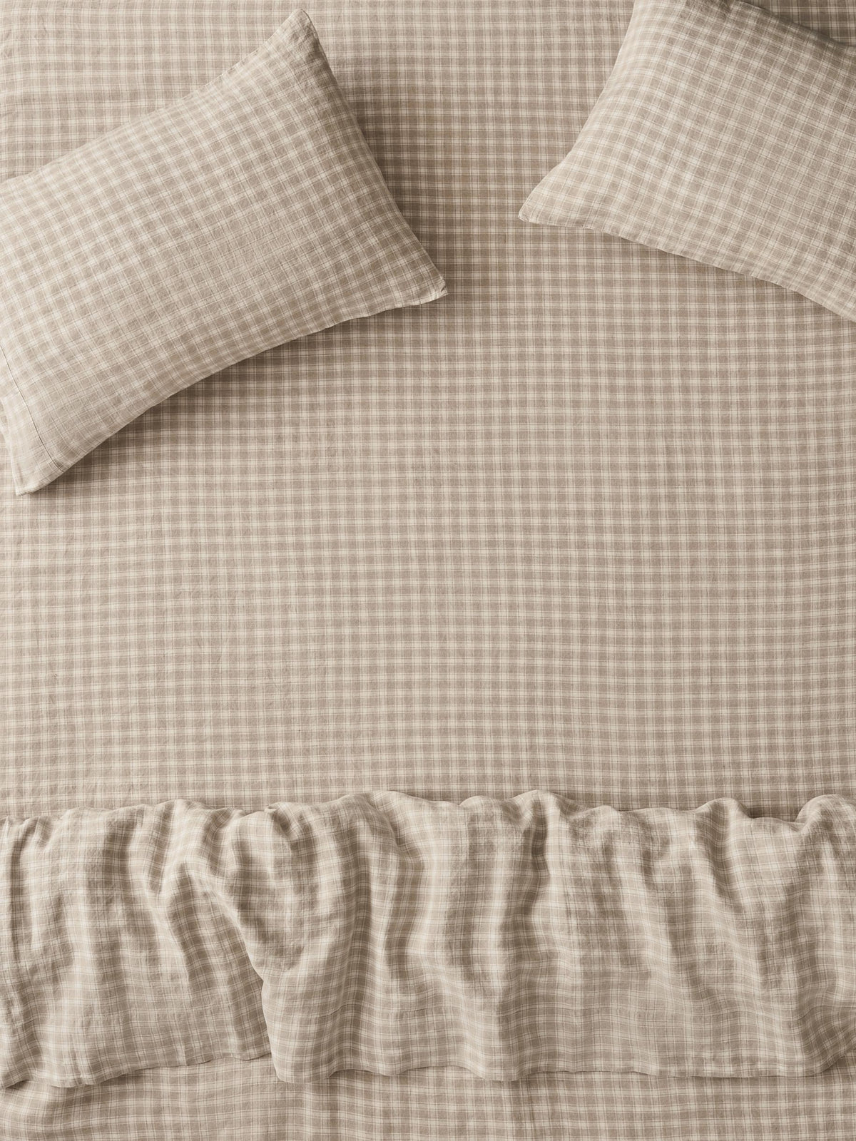 Beige and white gingham check bedding set with two pillows and a ruffled duvet cover.