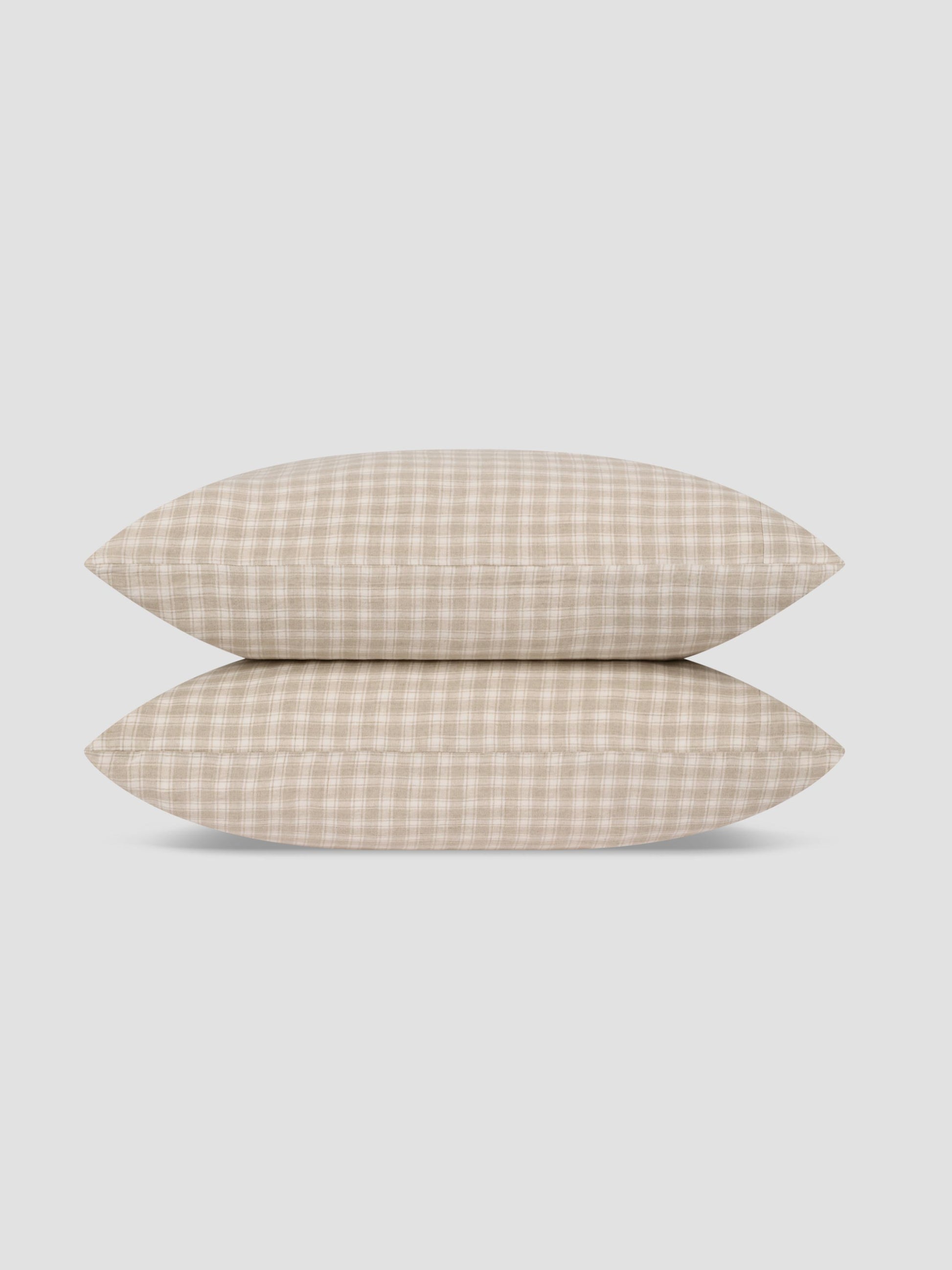 Two pillows stacked vertically, featuring a beige and white gingham checkered pattern, set against a solid light gray background.