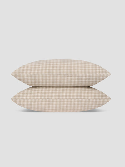 Two pillows stacked vertically, featuring a beige and white gingham checkered pattern, set against a solid light gray background.