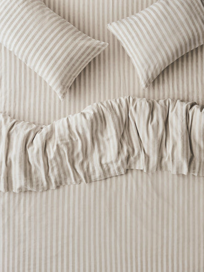 Striped bedding set with two matching pillowcases and a ruffled duvet cover in a warm beige and off-white color combination.