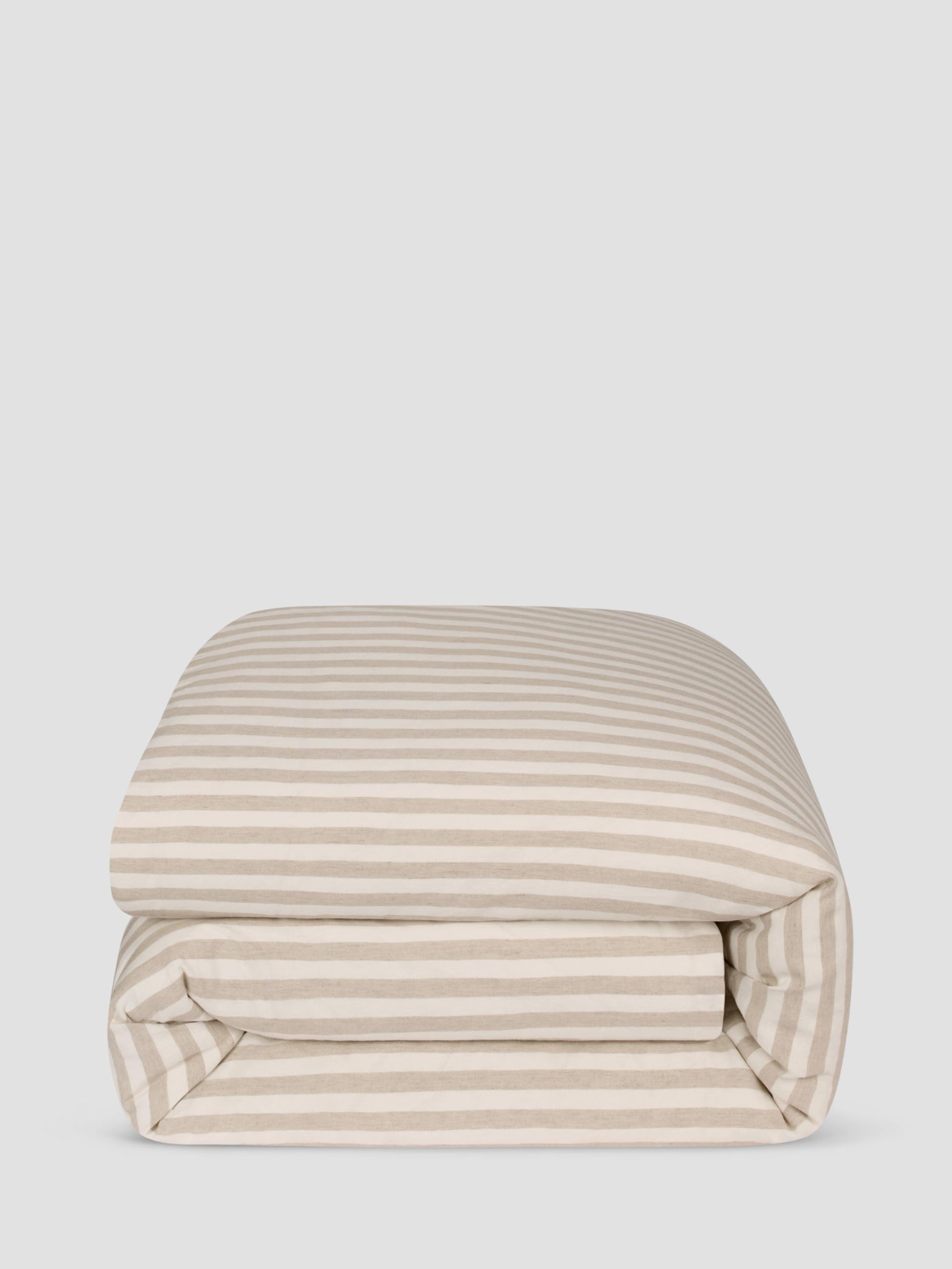 A folded comforter, featuring a horizontal stripe pattern in beige and off-white, set against a solid light gray background.
