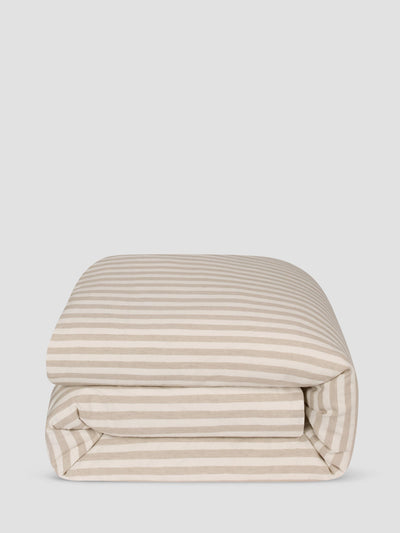 A folded comforter, featuring a horizontal stripe pattern in beige and off-white, set against a solid light gray background.