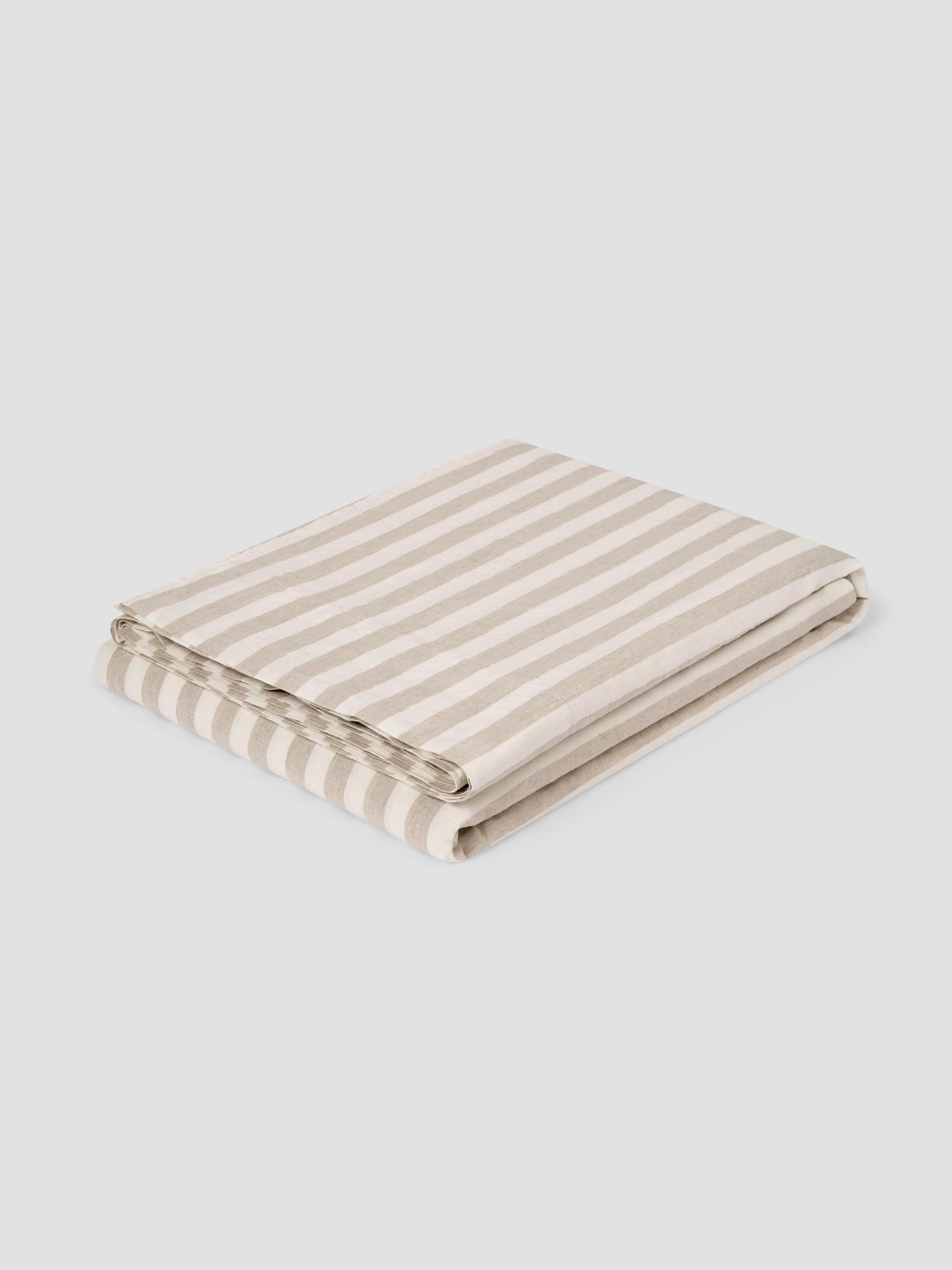 A folded striped flat sheet featuring alternating beige and off-white horizontal stripes, shown on a neutral light gray background.