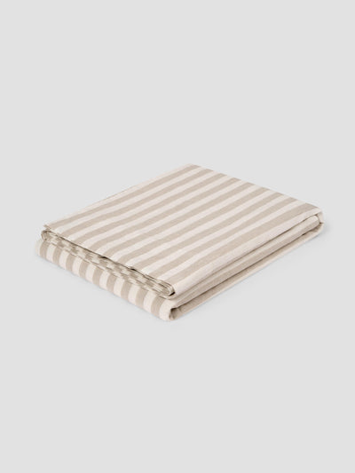 A folded striped flat sheet featuring alternating beige and off-white horizontal stripes, shown on a neutral light gray background.