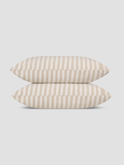 Two pillows stacked vertically, featuring a vertical stripe pattern in cream and light beige, set against a solid light gray background.