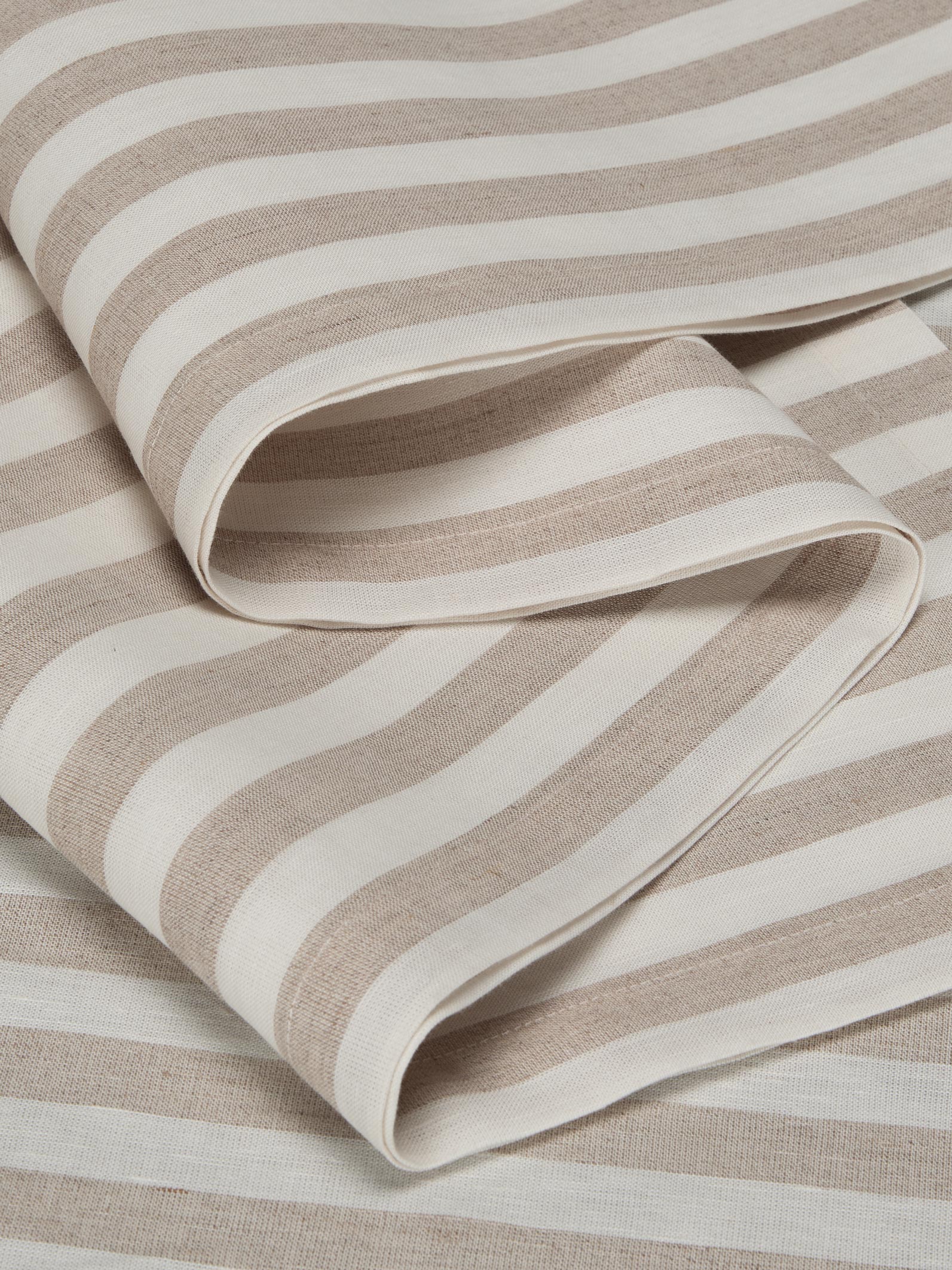 A close-up of folded striped fabric with alternating warm beige and off-white horizontal bands, showing a soft woven texture.