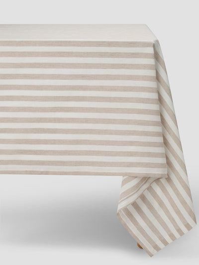 Oatmeal and white striped tablecloth draped over a table on a plain grey background