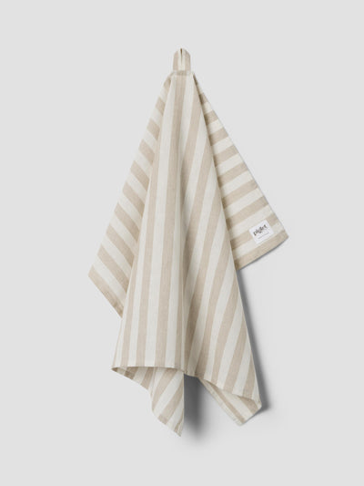 An oatmeal and white striped tea towel hanging up on a light grey background.