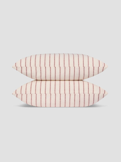 Two rectangular pillows stacked vertically, featuring a light pink and white stripe pattern with thin red vertical lines, set against a solid light gray background.