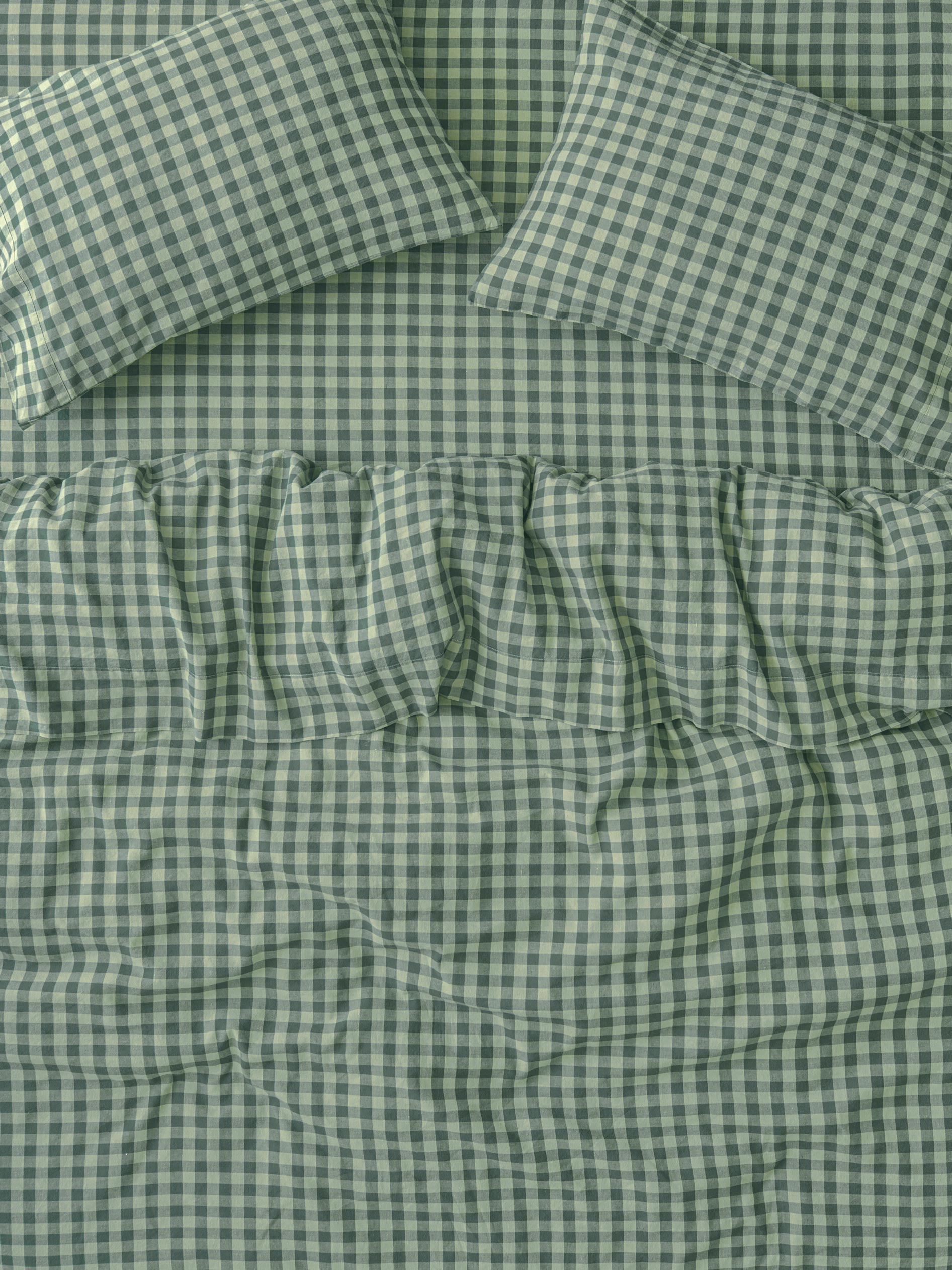 Green and white gingham check bedding set including a comforter and two matching pillowcases, shown in a close-up flat-lay view.
