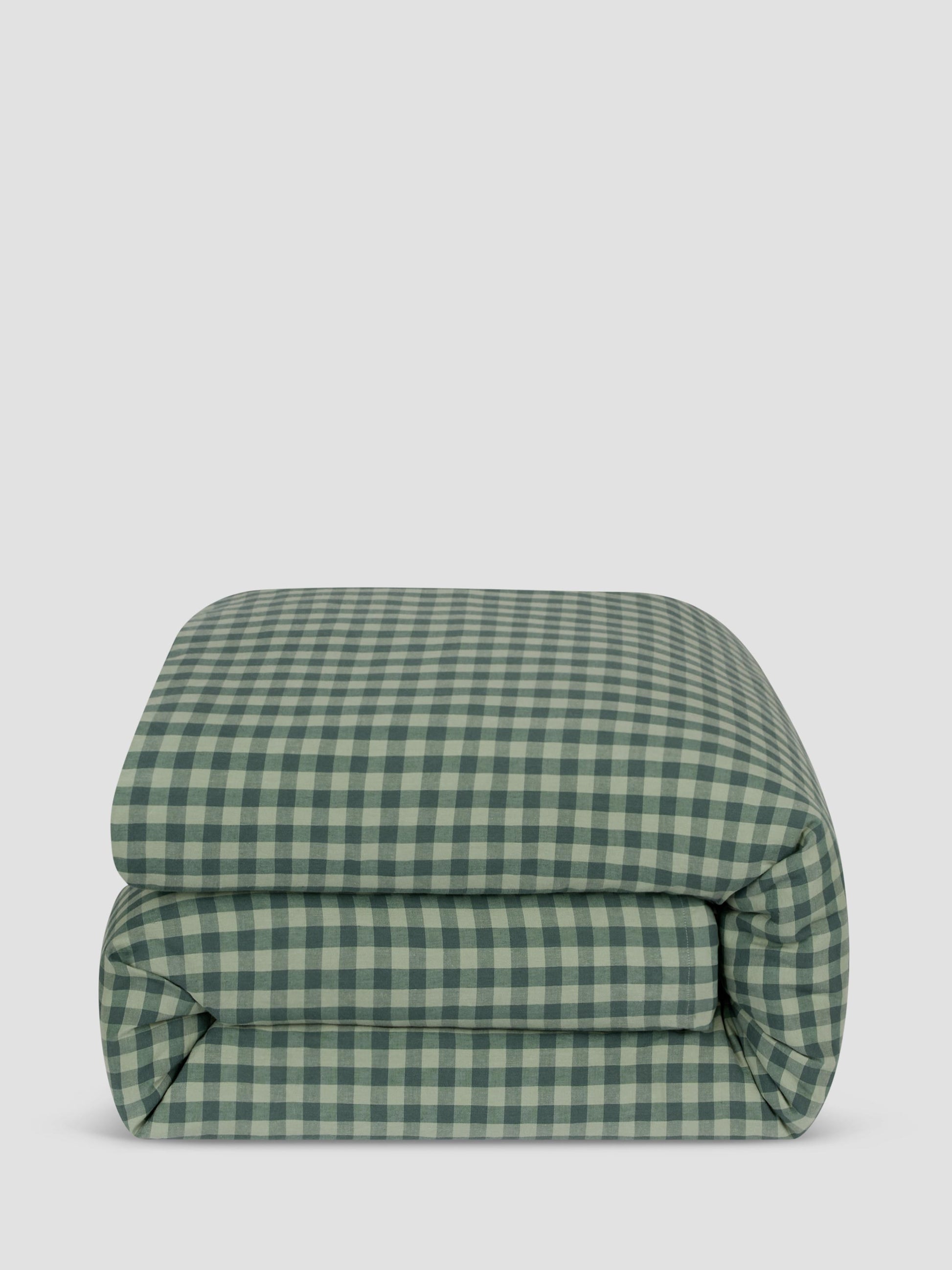 A folded green and white gingham checkered comforter, photographed against a solid light gray background.