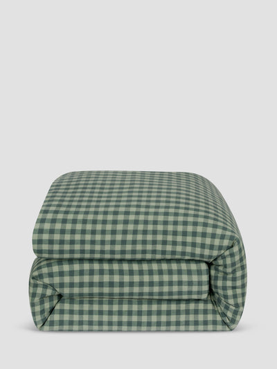 A folded green and white gingham checkered comforter, photographed against a solid light gray background.