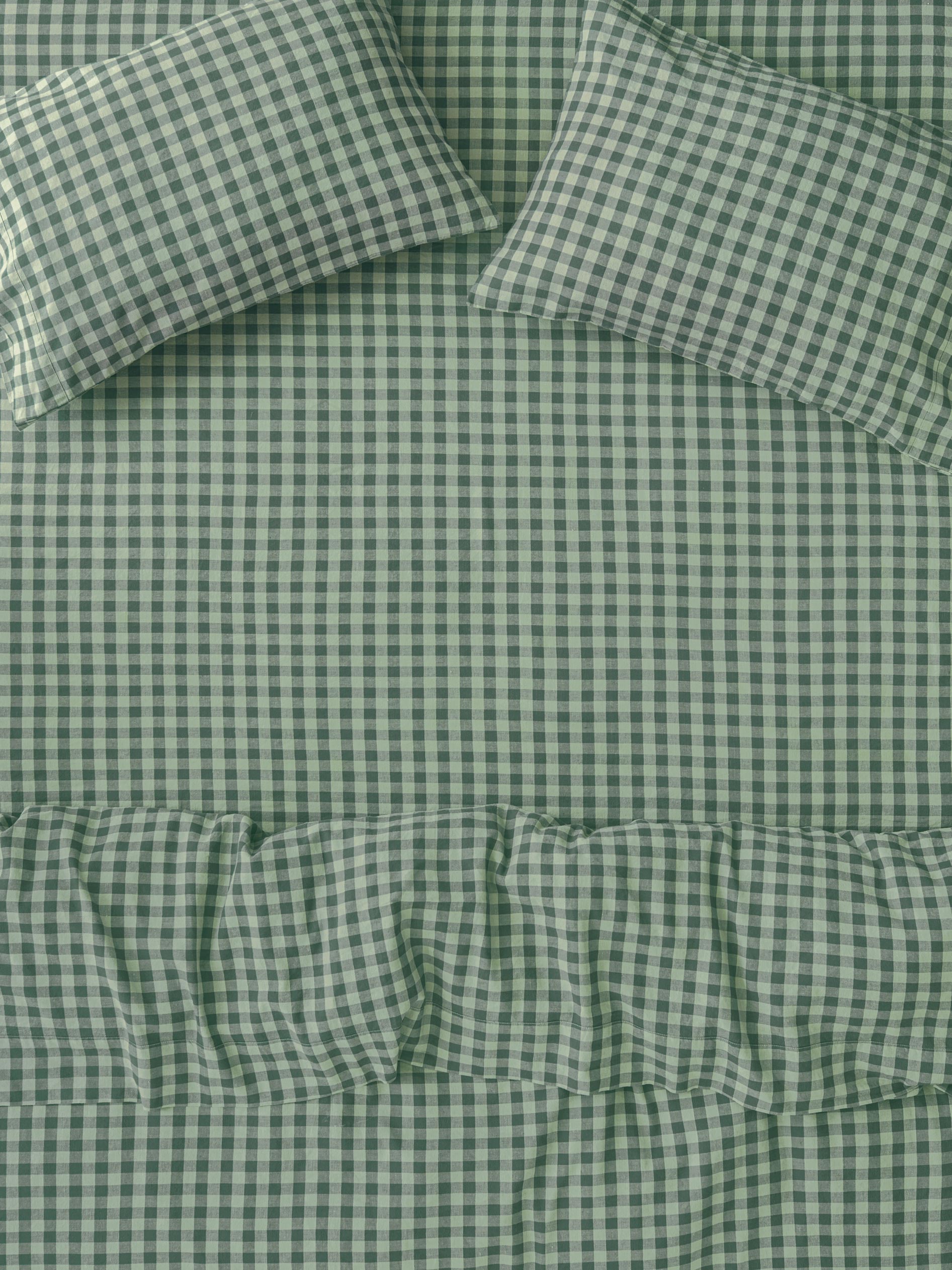 Green and white gingham check bedding set including a comforter and two matching pillowcases, featuring a ruffled edge detail on the comforter.