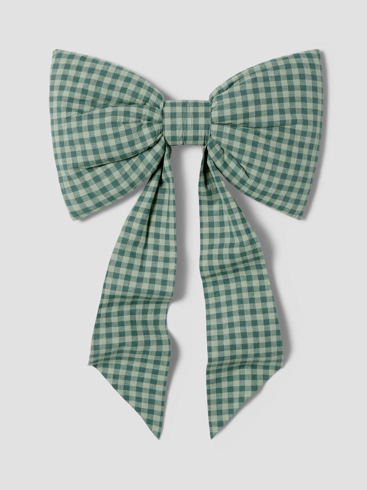 A large fabric bow in a green and white gingham check pattern, photographed flat against a light gray background.