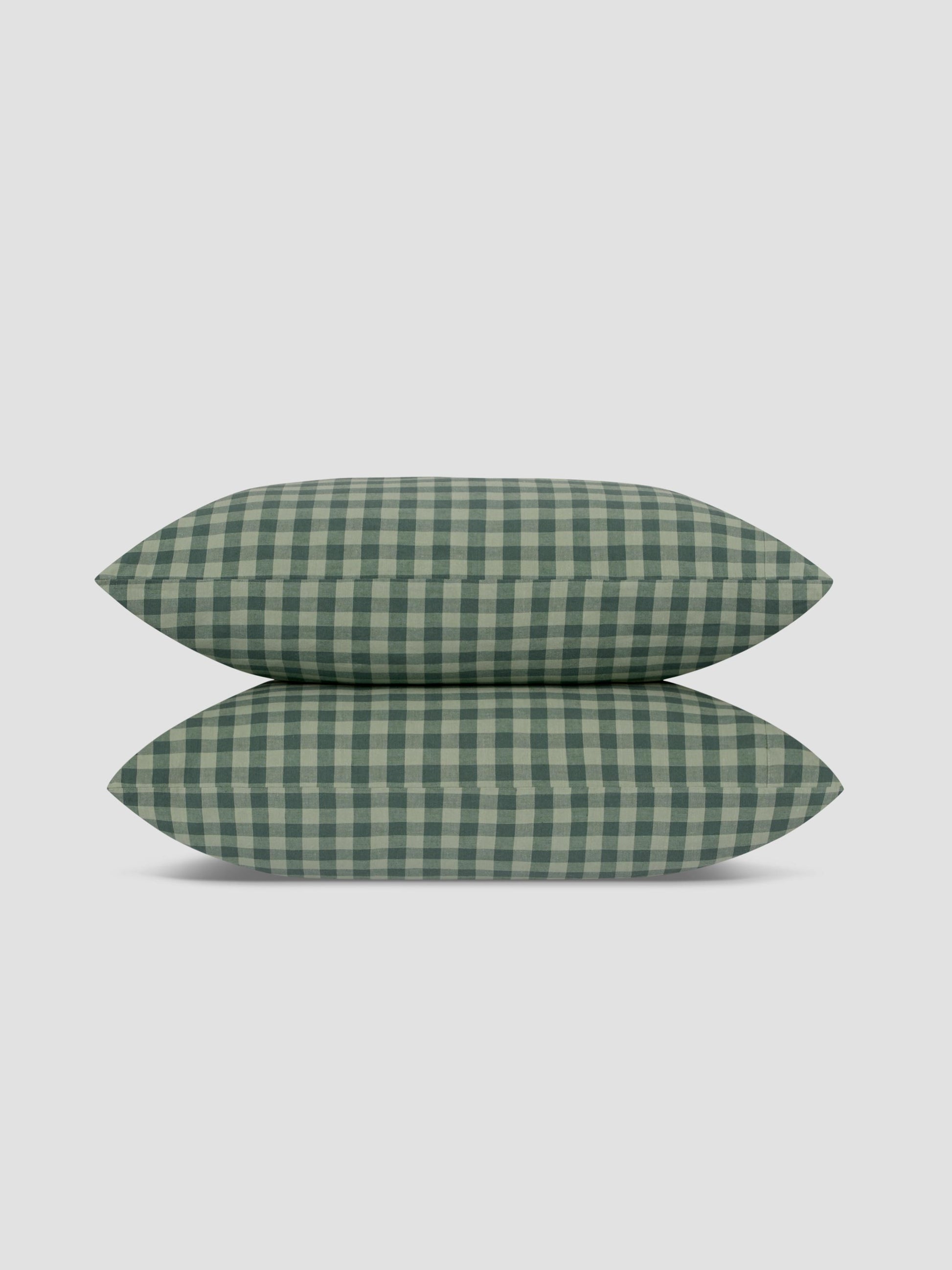 Two green and white gingham checkered pillows stacked vertically on a light gray background.