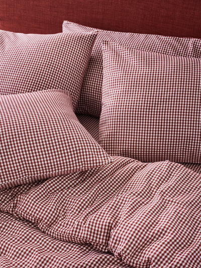 Four pillows and a duvet cover  with a red and white gingham check pattern.