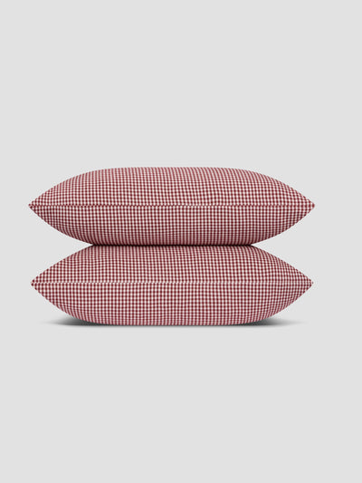 Two pillows stacked on top of each other with a red and white gingham check pattern.