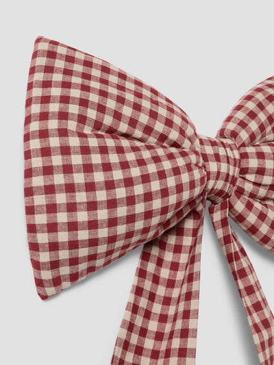 A red and cream gingham check bow on a light gray background.