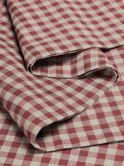 A close-up of folded red and off-white gingham checkered fabric, showing its woven texture and pattern.