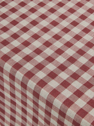 A close-up of a red and oatmeal gingham checkered tablecloth draped to show its texture and pattern.