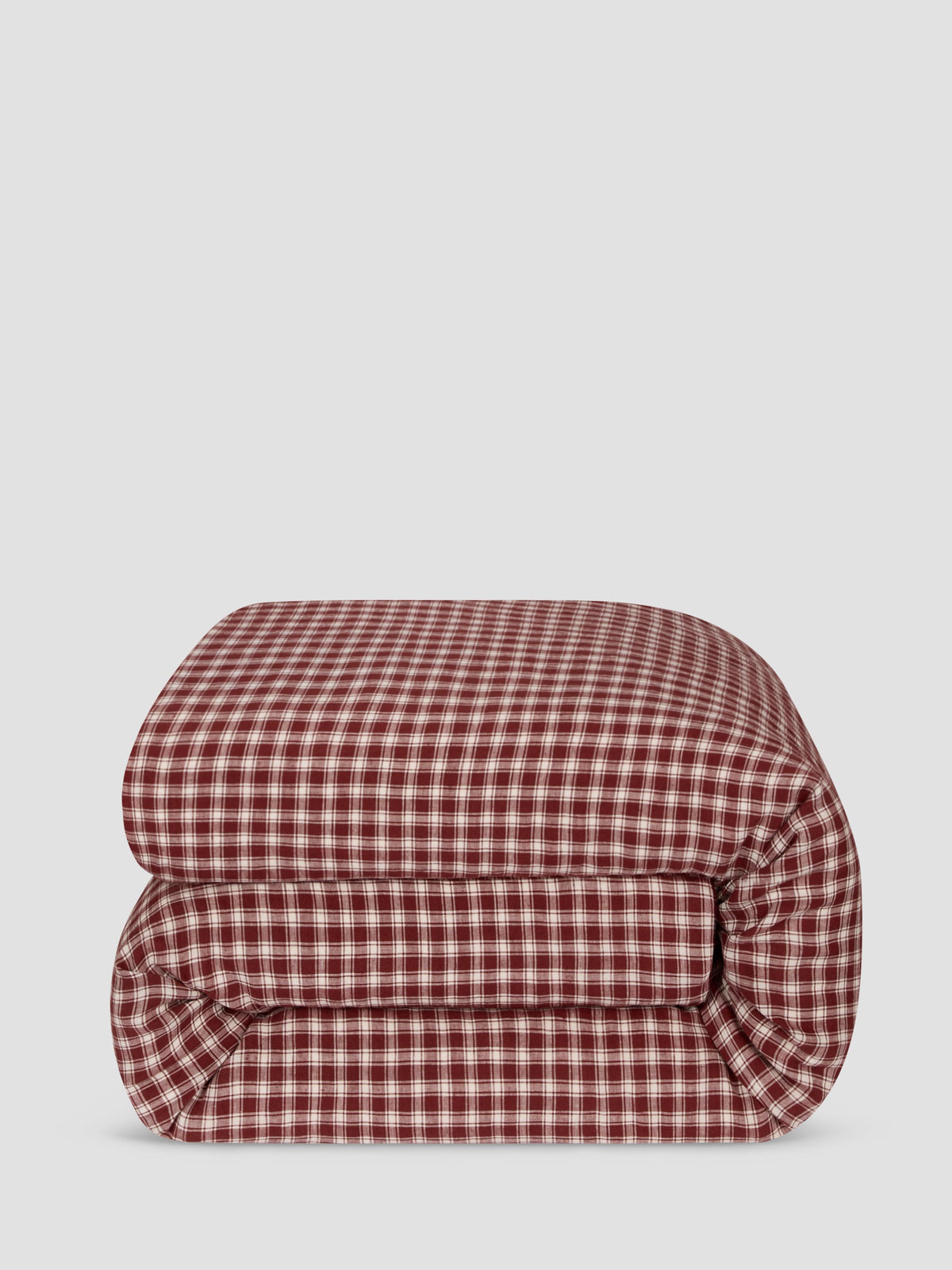 A folded red and white gingham checkered blanket or comforter, shown against a solid light gray background.
