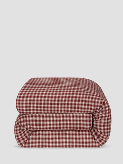 A folded red and white gingham checkered blanket or comforter, shown against a solid light gray background.